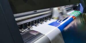 A large printing machine operates on a big sheet of paper, showcasing Boise printing materials in action.