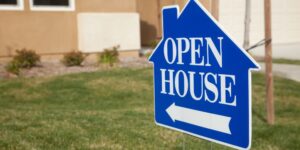 A house with a blue open house sign displayed outside, welcoming potential buyers.