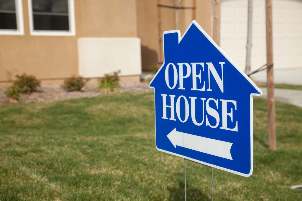 A house with a blue open house sign displayed outside, welcoming potential buyers.