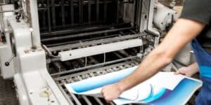 A man operates a printing machine, showcasing event printing services Boise in action.